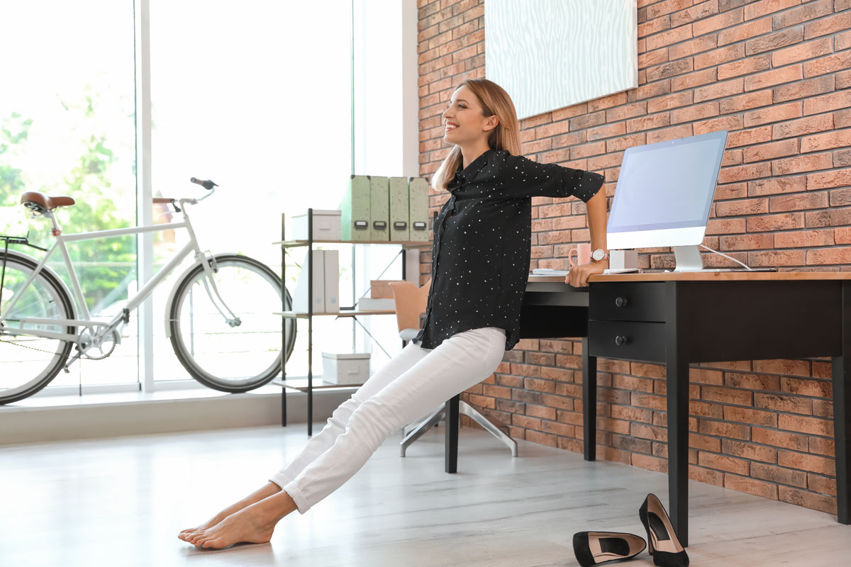 FirmenFitness Mobiles Coaching Paket - Büro-Mitarbeiterin macht eine Übung am Schreibtisch